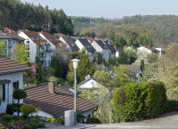 Blick über die am Berghang gelegenen Häuser in Erzhütten/Wiesenthalerhof. Die Bäume und Blumen stehen in voller Blüte und beherrschen den Großteil des Bildes.