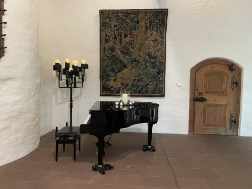 Der Flügel neben der Eingangstür des Pfalzgrafensaals, dahinter ein großer Kerzenleuchter und ein Wandteppich.