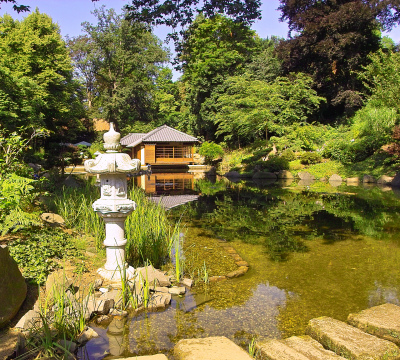 Teehaus am großen Teich im Japanischen Garten. Eine kleine Steinbrücke führt über den See.