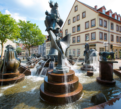 Man sieht den Kaiserbrunnen in Kaiserslautern mit seinen Abbildungen von Fischen,Elefanten etc.  Ganz oben ist gut die Statue des Kaisers zu sehen.