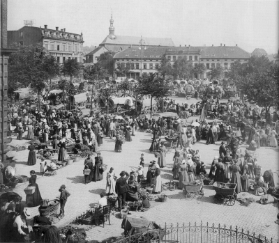 Der Stiftsplatz ist von unterschiedlichsten Besuchern bevölkert. Im Hintergrund sind Pferdefuhrwerke zu erkennen und vorne werden auf Decken und Körben Eigenerzeugnisse verkauft.