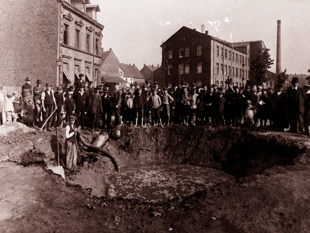 Bürger Kaiserslauterns stehen versammelt vor einem großen Krater, der sich mit Wasser gefüllt hat.  © Stadtarchiv