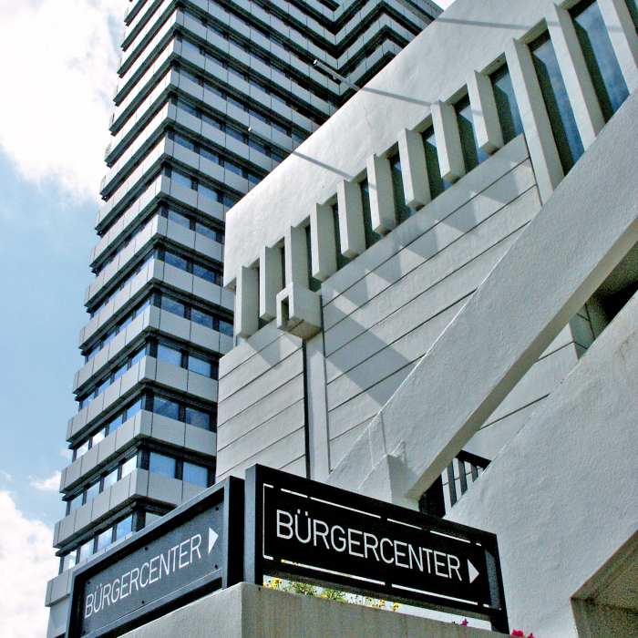 Eingangsschilder des Bürgercenters mit Rathausgebäude im Hintergrund