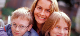 Einen Blick auf eine junge Mutter mit ihren beiden Kindern, die in die Kamera lächeln
