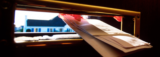 Einwurf von Post durch einen Briefschlitz in der Haustür 
