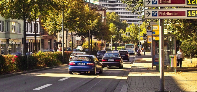 Man blickt die Rudolf-Breitscheid-Straße hinunter in Richtung Rathaus. Mehrere Autos und ein Bus fahren auf dieser Straße über eine grüne Ampel. Direkt vor dem Betrachter steht eine Bushaltestelle. © Stadt Kaiserslautern