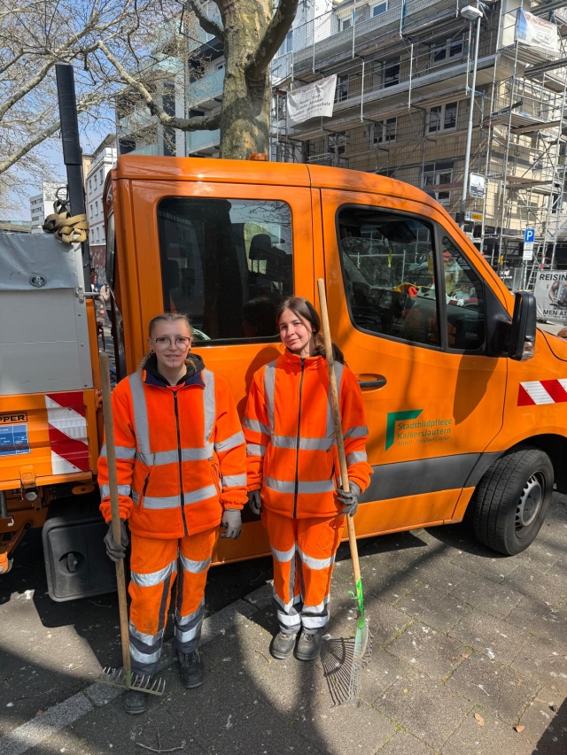 Oceane und Luna stehen mit Rechen in der Hand vor einem Fahrzeug der SK. © Stadtbildpflege Kaiserslautern