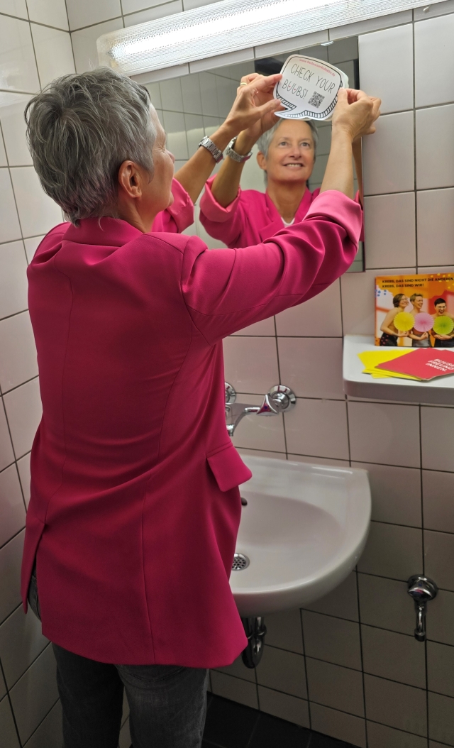 Oberbürgermeisterin Beate Kimmel bringt Aufklärungssticker an Badspiegel an. © Stadt Kaiserslautern