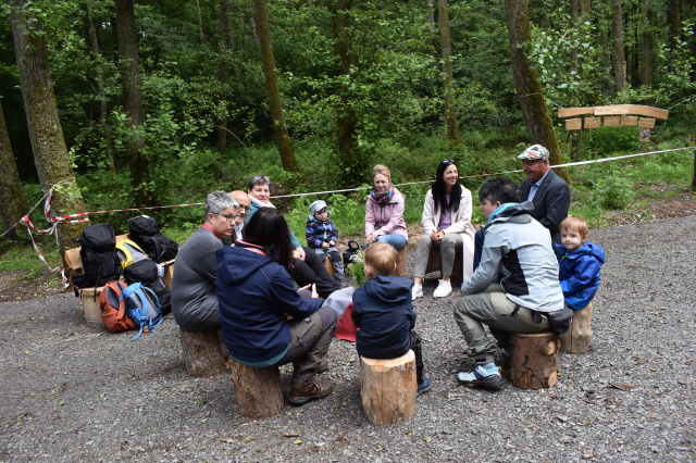 Probieren die naturnahen Sitzgelegenheiten aus: Anja Pfeiffer, Zoodirektor Matthias Schmidt, Kinder und Erzieherinnen des Zookindergartens, sowie Vertreterinnen und Vertreter der Stadtverwaltung. © Stadt Kaiserslautern