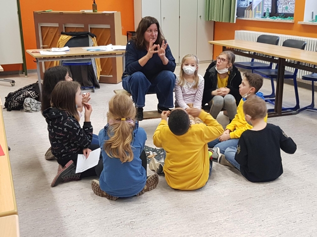 Auf dem Bild ist Schriftstellerin Christina Bacher mit den Kindern der Kottenschule zu sehen. © Stadt Kaiserslautern