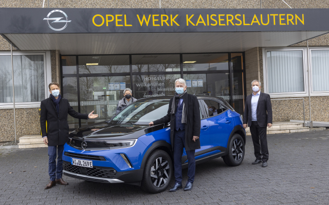 Das Foto zeigt Uwe Hochgeschurtz, Beate Kimmel, OB Klaus Weichel und Stefan Weiler mit einem blauen Opel-Neuwagen vor dem Werkseingang.
 © Opel Automobile GmbH