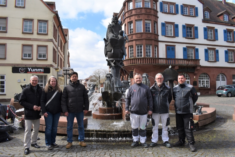 V.l. Udo Holzmann, Leiter des Referats Gebäudewirtschaft, Nadine Weber, Abteilungsleiterin Bauausführung und Gebäudeerhaltung, Beigeordneter Manuel Steinbrenner und die Mitarbeiter der Gebäudeerhaltung freuen sich bei schönstem Sonnenschein über den Beginn der Brunnensaison in Kaiserslautern. © Stadt Kaiserslautern