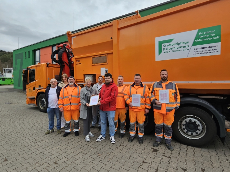 Beate Kimmel, Kristian Fink und die weiteren Beteiligten stehen vor einem Müllfahrzeug und halten den Appell und die Unterschriften in die Kamera. © Stadt Kaiserslautern