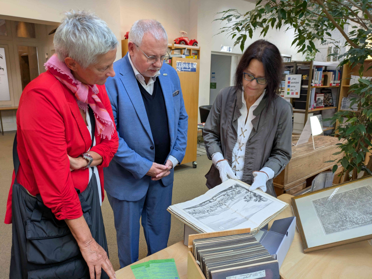 Oberbürgermeisterin Beate Kimmel und Bezirkstagsvorsitzender Hans-Ulrich Ihlenfeld betrachten mit Bibliotheksleitung Claudia Germann einen historischen Stich der Stadt Kaiserslautern. © Bezirksverband Pfalz