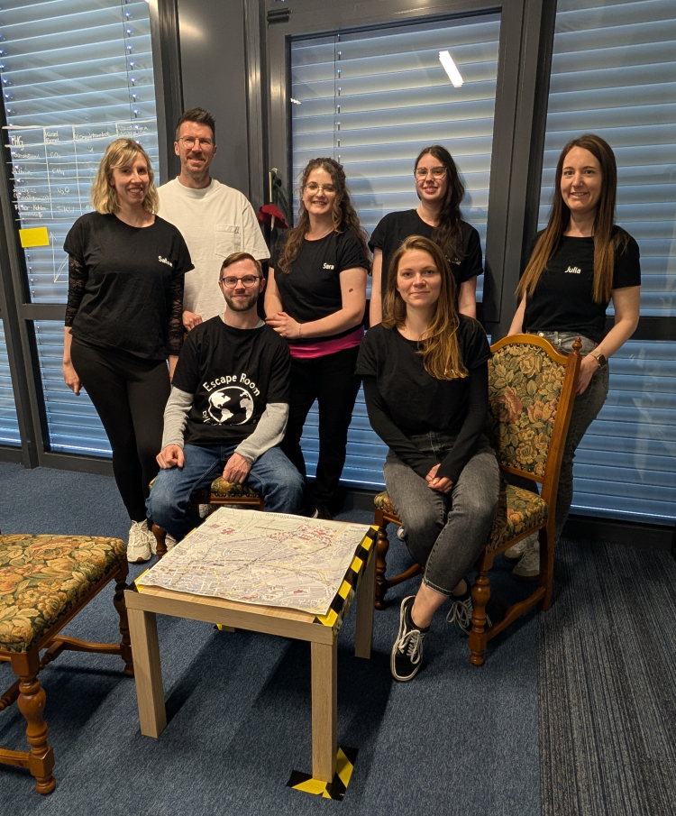 Das Team rund um den Escape Room (v.l.n.r.): Sabine Martin (42kaiserslautern), Marco Zettl (EUROPE DIRECT), Sara Mohr (Kreisverwaltung Kaiserslautern), Celine Wesseling (Kreisverwaltung Kaiserslautern),  Julia Merscher (Stadtverwaltung Kaiserslautern), sitzend: Patrick Glaser (Herzlich digital), Anja Jung (Stadtverwaltung Kaiserslautern) © 42kaiserslautern