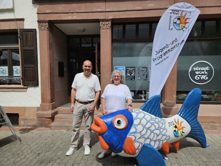 Bürgermeister Manfred Schulz mit JUZ-Leiterin Nicole Junk vor dem Eingang des Hauses mit dem neu bemalten JUZ-Fisch Jakkie. © Stadt Kaiserslautern