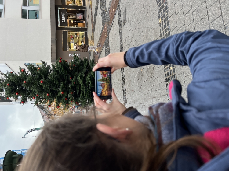 Eine Frau schaut sich ein Augmented-Reality-Bild der Tanne in der Fackelstraße auf ihrem Smartphone an. © herzlich digital