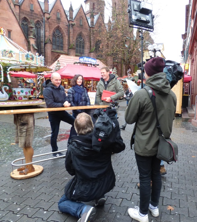 Dreh der SWR-Sendung Stadt Land Quiz auf dem Kaiserslauterer Weihnachtsmarkt: Moderator Jens Hübschen (rechts) stellt den Kaiserslauterer Stadtpaten Andrea Stephany(Mitte) und Matthias Pallmann (links) eine knifflige Tagesaufgabe © Stadt Kaiserslautern