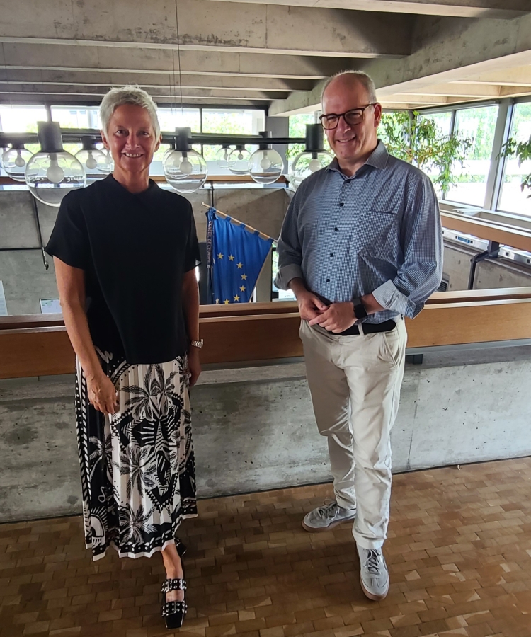 Beate Kimmel und Norbert Herhammer stehen auf der Galerie im oberen Foyer des Rathauses, im Hintergrund die EU-Flagge © Stadt Kaiserslautern