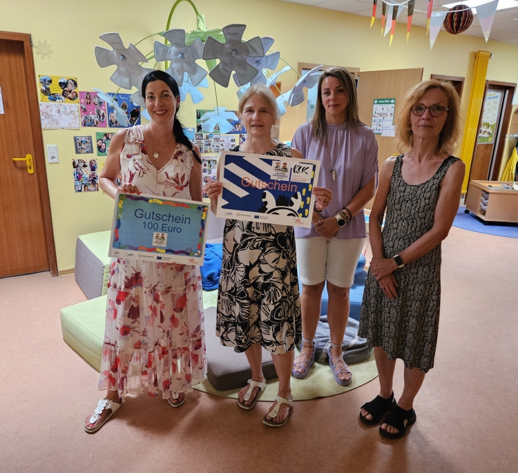 Die Leiterin der Kita, Gabriele Franzinger, präsentiert den Gutschein für den Besuch der Kinderunfallkommission. Anja Pfeiffer hält den Gutschein über 100 Euro, den alle teilnehmenden Kitas erhielten. Rechts Nina Hajda vom Referat Stadtentwicklung und Sabine Michels vom Bildungsbüro.  © Stadt Kaiserslautern