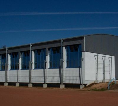 graues Schulgebäude mit blauen Fensterrahmen im Sonnenlicht
