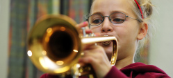 Junges Mädchen spielt konzentriert auf einer Trompete.