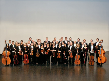 Die Musiker des Orchesters mit ihren Instrumenten. Vorne sind die Streicher zu sehen und hinen die Bläser. © Pfalzphilharmonie Kaiserslautern