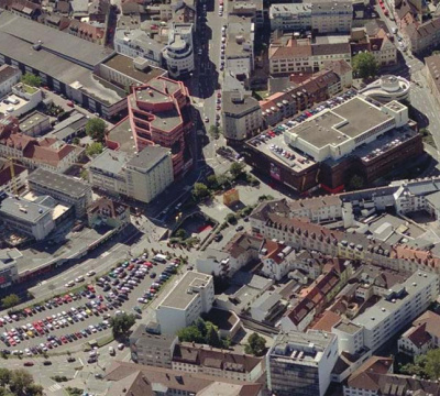 Luftaufnahme vom Karstadtgebäude und dem davor liegenden Parkplatz.