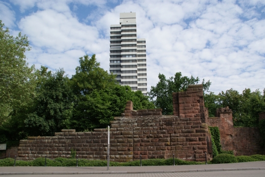 Das Mauerwerk der ehemaligen Kaiserpfalz umgeben von grünen Bäumen und Büschen. Dahinter ist das Rathaus zu erkennen. © PRtext 
