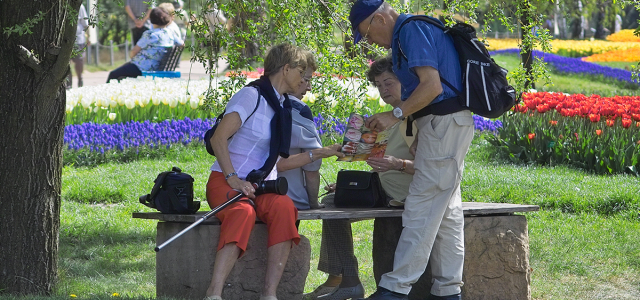 Gruppe von Senioren, die sich auf der Gartenschau mit einem Prospekt informiert