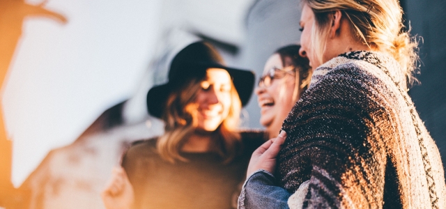 Drei Frauen in einer Stadt, die lachen und sich freuen.