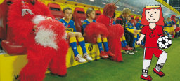 Der kleine Friedrich macht sich am Spielfeldrand mit einem Fußball warm.Auf der Trainerbank hinter ihm sitzen einige Maskottchen des FCK und Kinder.