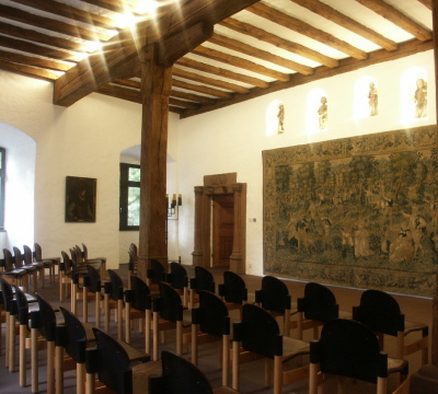 Blick in den Pfalzgrafensaal mit Bestuhlung. Im Hintergrund sieht man den historischen Wandteppich.