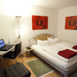 Ein modernes Hotelzimmer im Rosenhof mit Doppelbett und Sitzmöglichkeiten.