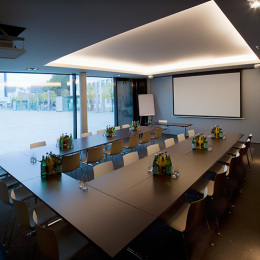 The tables of the conference room are arranged in a U-shape. Several islands of drinks and glasses are standing on the tables.
A whiteboard and flip chart are available for conferences. The room is on the ground floor of the hotel.