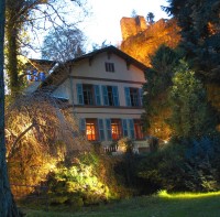 The Villa Denis is surrounded by trees and shrubs and about the building there is an old ruin.