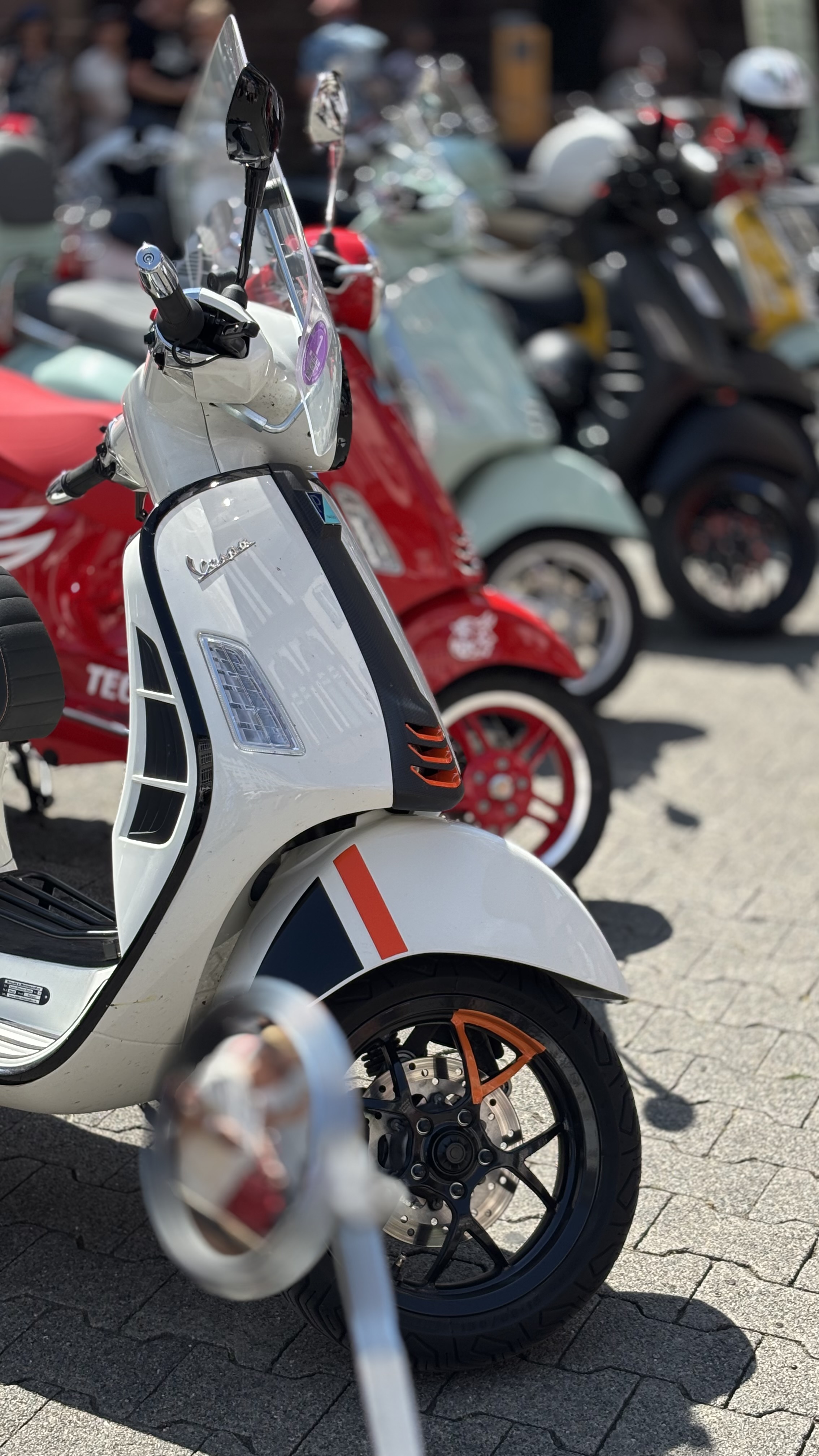 Das Bild zeigt mehrere farbige Vespas hintereinander in einer Reihe.