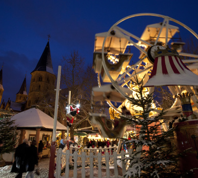 Im Vordergrund sieht man den Weihnachtsmarkt, im Hintergrund die Stiftskirche
