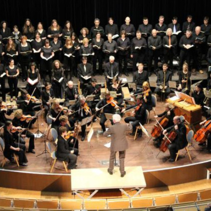 Der Klassische Chor der TU Kaiserslautern auf der Bühne - Sängerinnen und Sänger mit Orchester und Dirigent während einer Performance